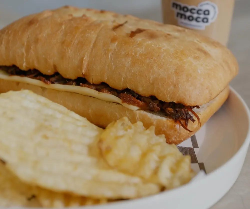 Chapata con papas en plato blanco y un latte de mocca moca atrás